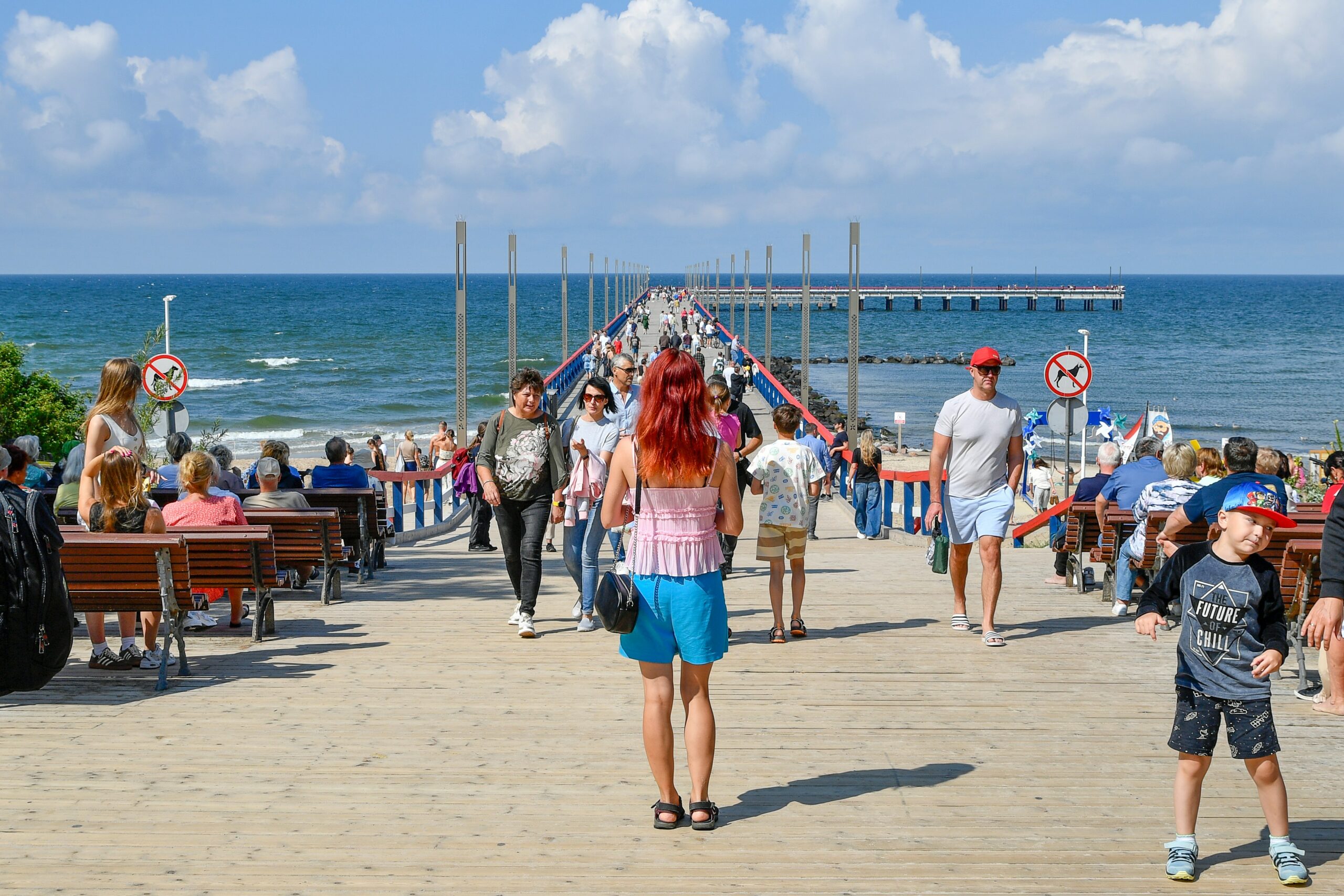 A small crowd gathered at the end of the pier watching a fish come up